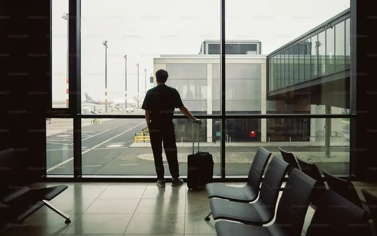 Person am Flughafenfenster blickt auf ein Flugzeug