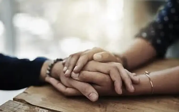 Zwei Menschen halten einander die Hand