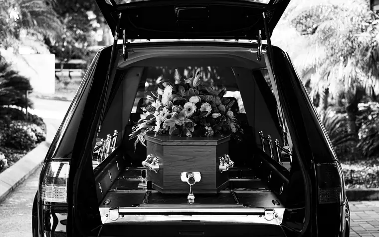 Bestattungsfahrzeug mit Sarg und Blumenschmuck