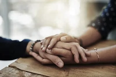 Zwei Menschen halten einander die Hand