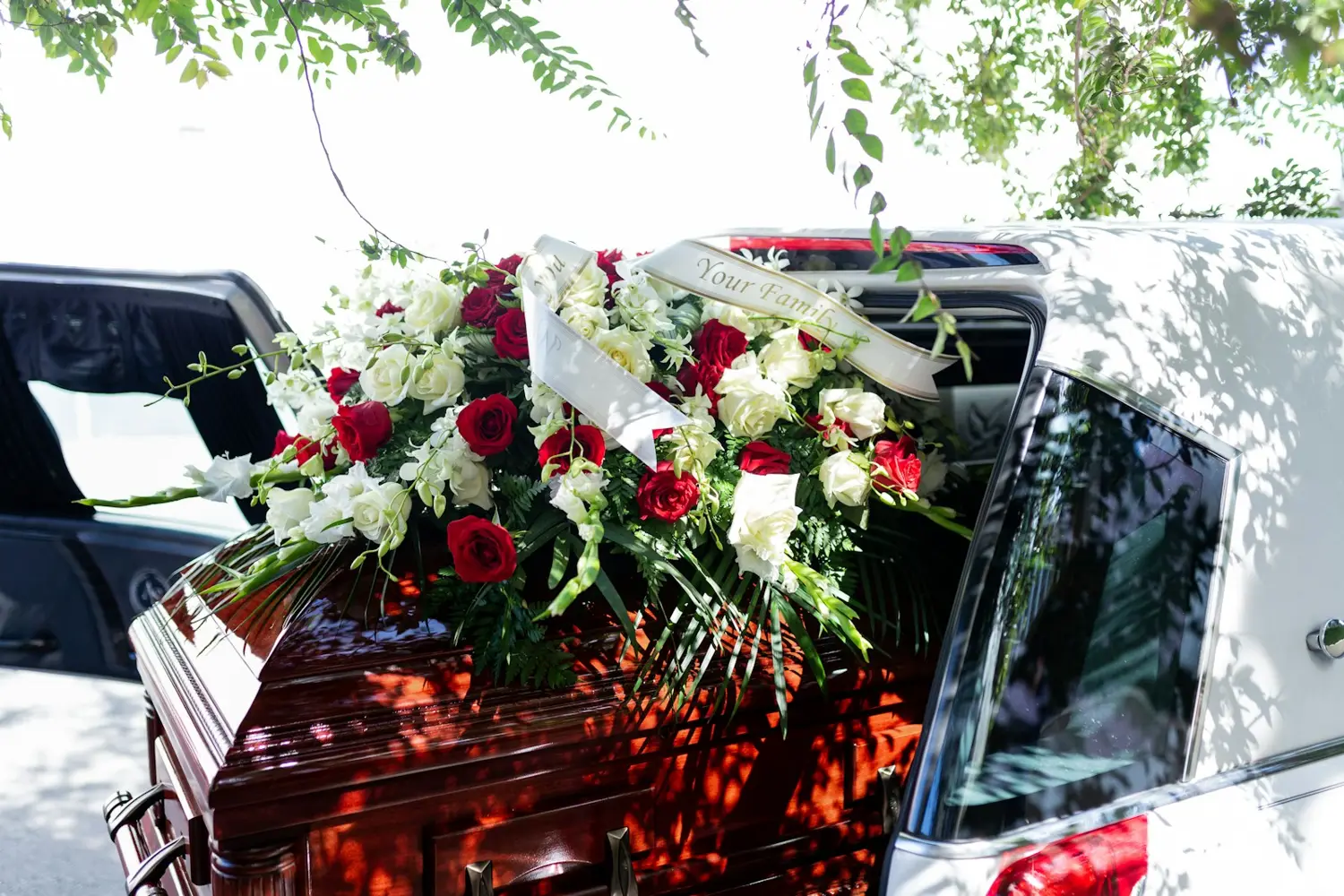 Sarg mit Rosengesteck im Bestattungswagen